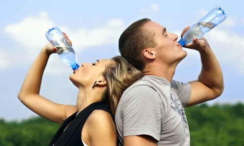 couple buvant de l'eau en bouteille